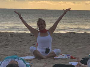 View of yoga teacher stretching her arms up to the sky