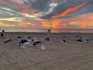 View of yoga class on the beach during sunset