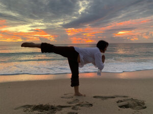 View of woman doing a yoga pose as the water moves towards her