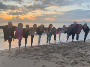 Stress Less Yoga Retreat - 12 people in a yoga pose on the beach at sunrise