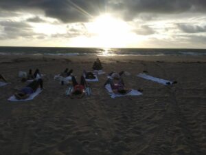 students laying on the beach as the sun goes down