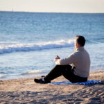 View of man sitting on a towel on the beach