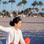 View of student doing yoga on the beach