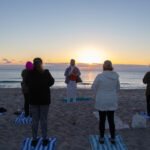 Front view of woman teaching a class on the beach.