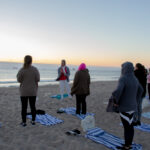 Woman teaching a class on the beach.